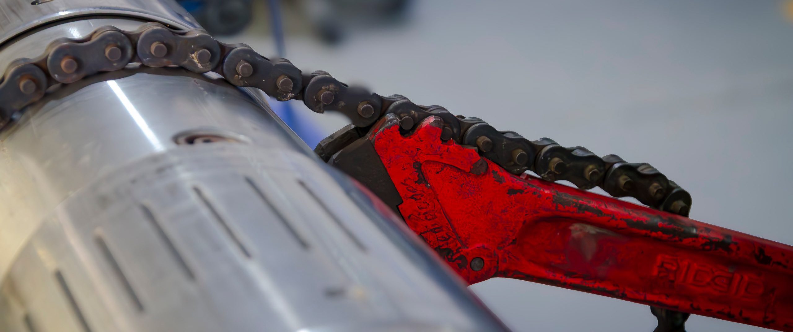 Close-up of a rotary steerable tool body held by a red chain wrench