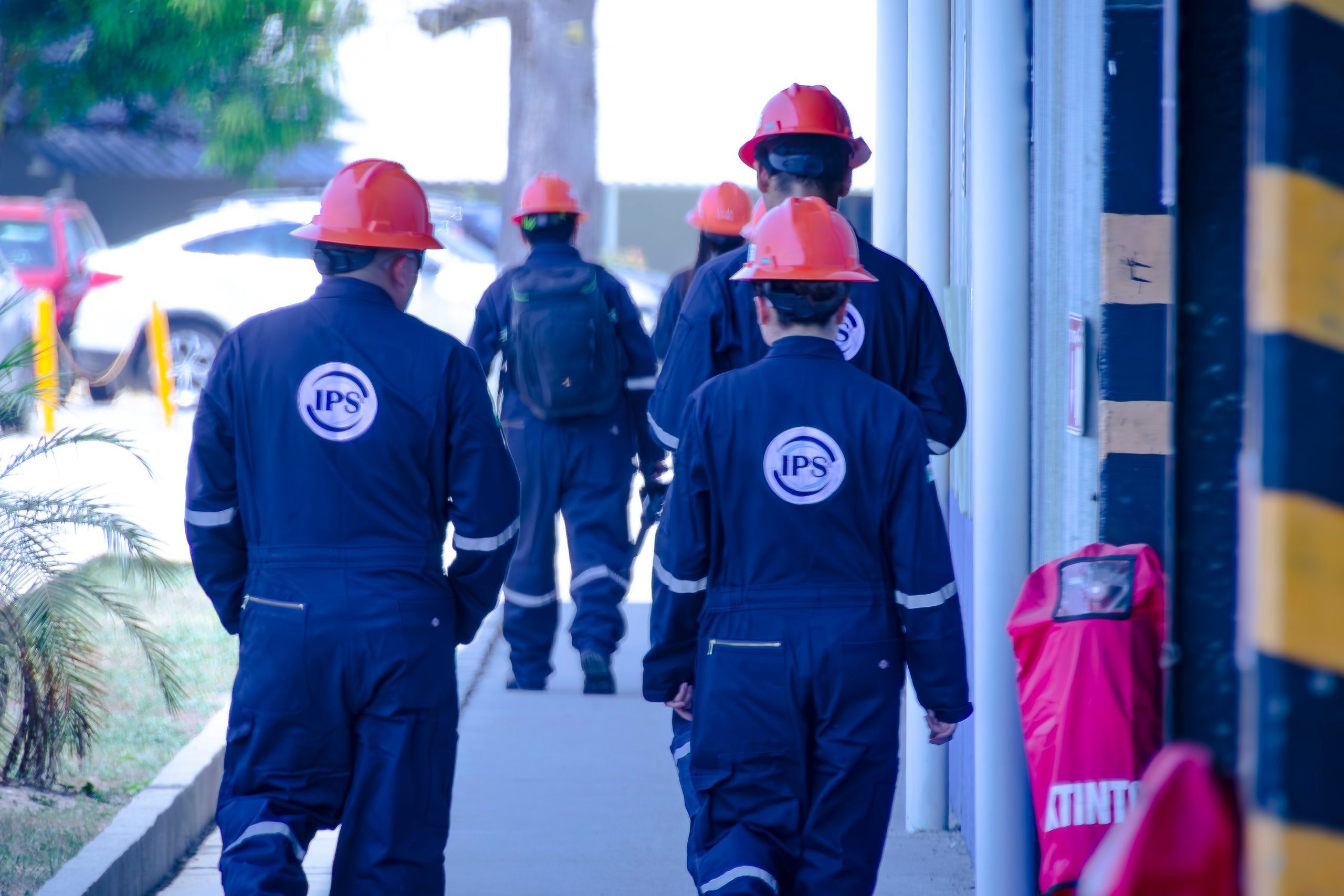 Grupo IPS field crew in hard hats and coveralls walking through the base