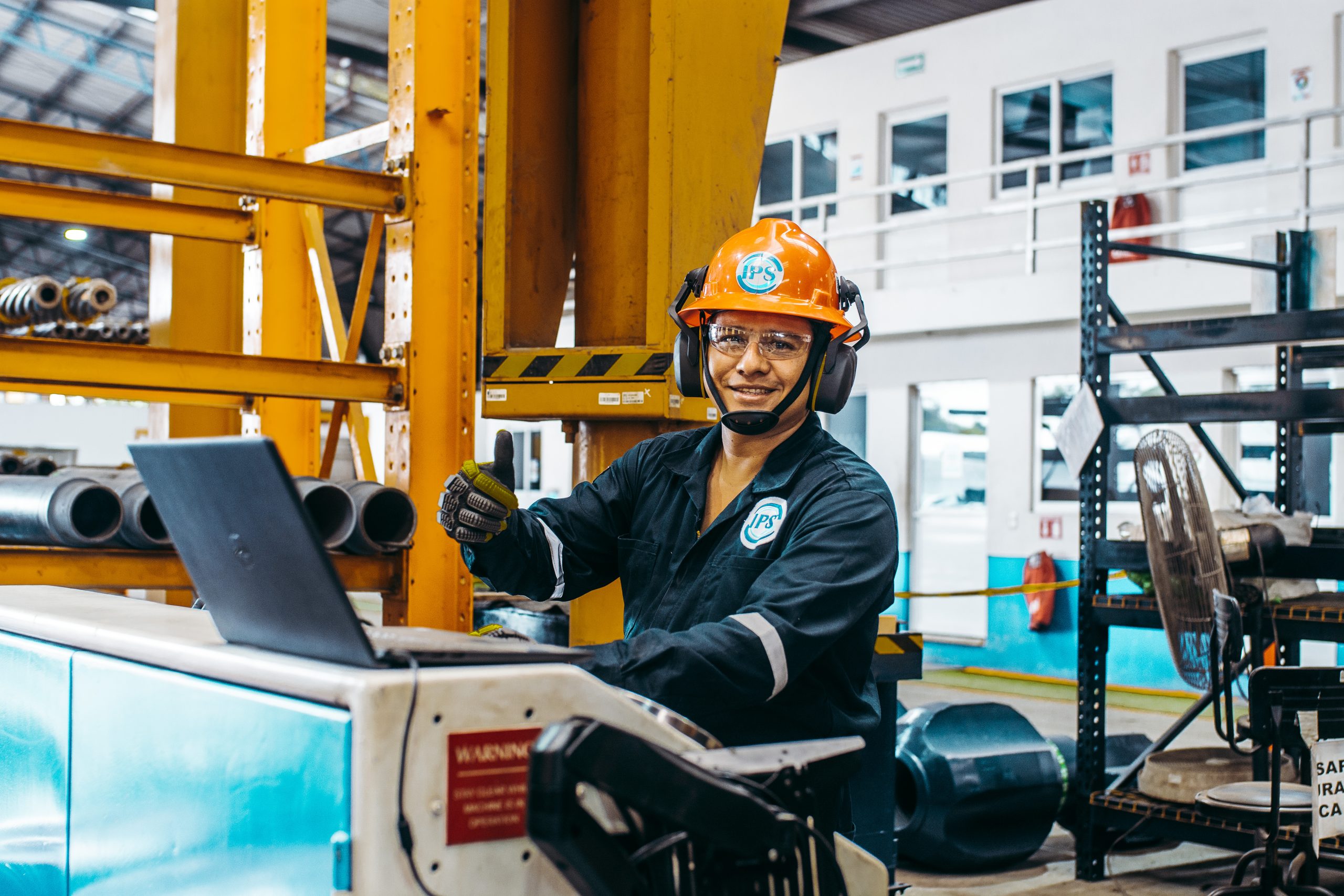 Technician giving a thumbs up beside a laptop in the workshop