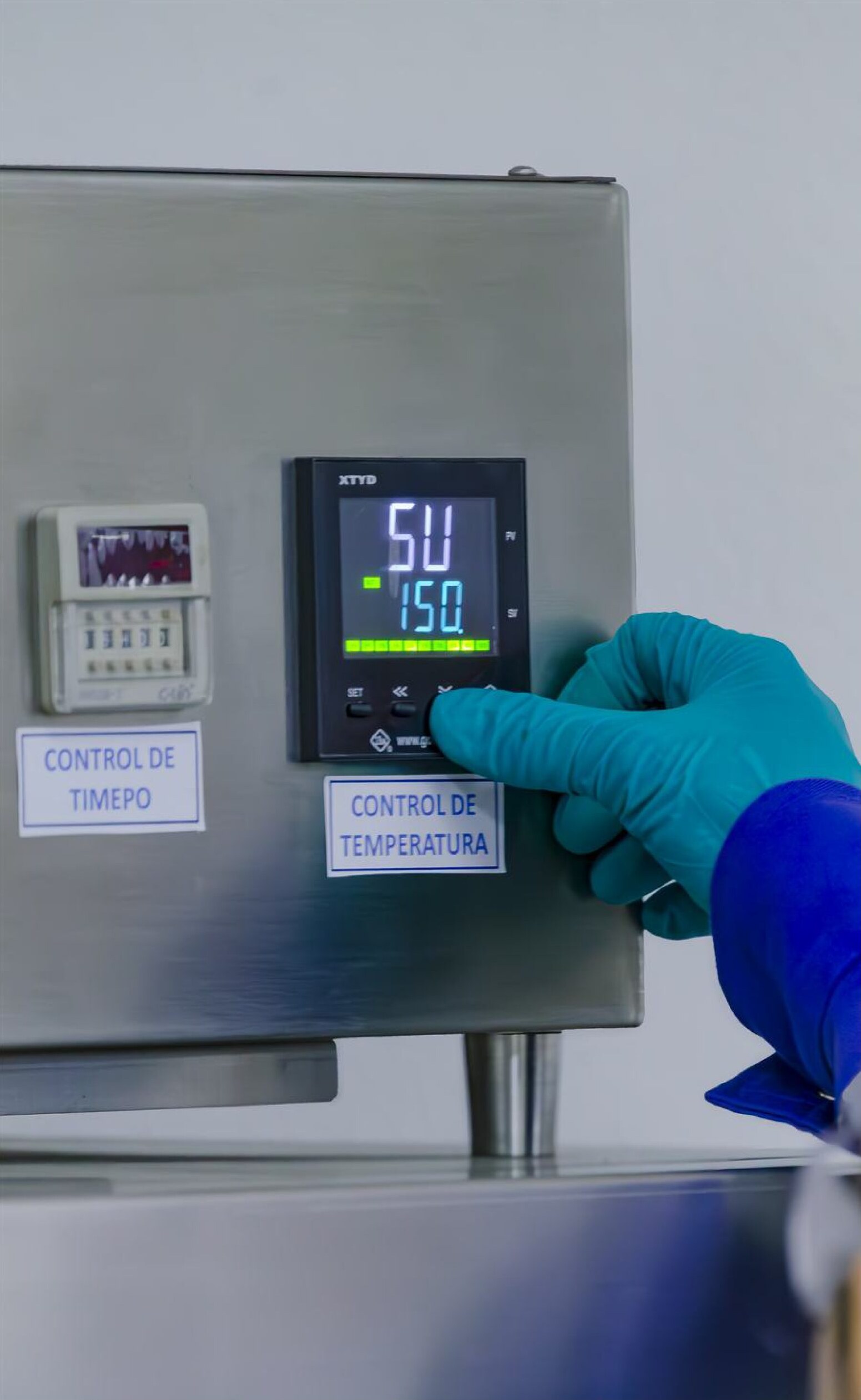 Gloved hand setting a temperature controller