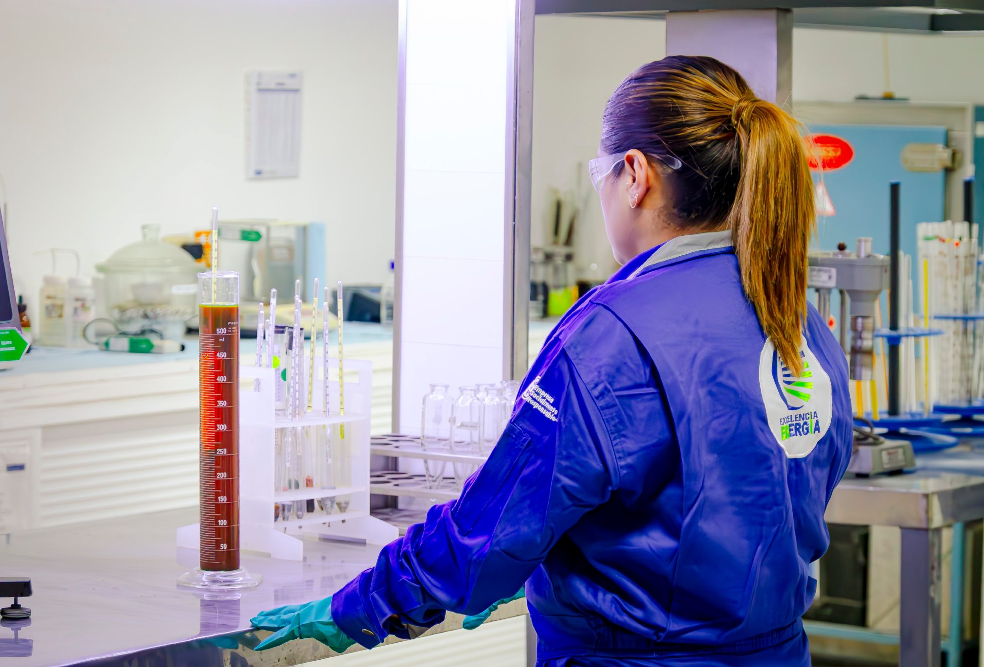 Laboratory technician handling a graduated cylinder with a fluid sample